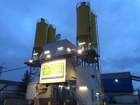 Nieuwe betoncentrale met gele cementsilo's in de schemering